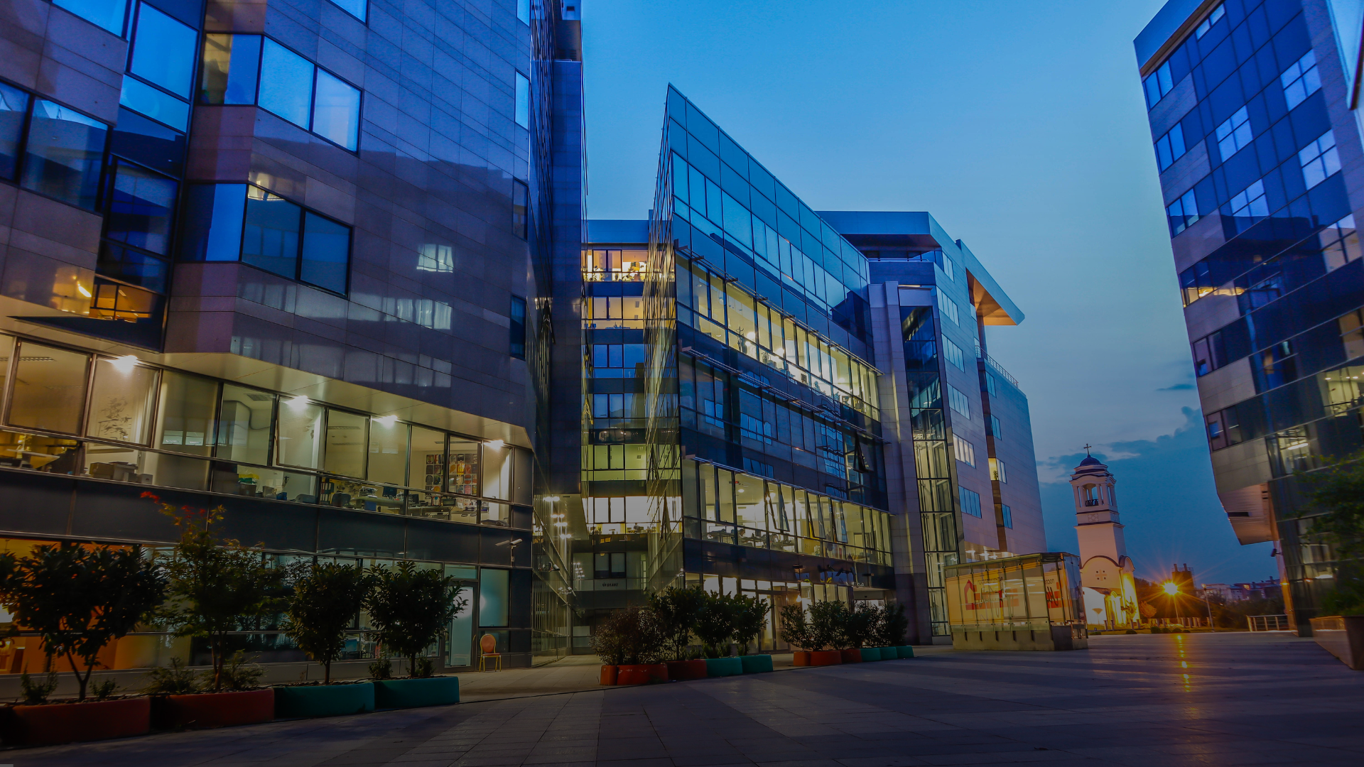 A row of modern commercial buildings at dusk with lights on
